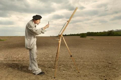Painter measuring scale and working on new canvas painting directly in field Stock Photos
