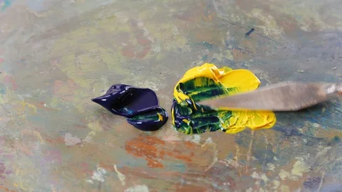 A painter mixes blue and yellow colors on a palette Stock Footage 86868554
