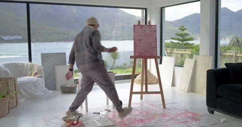 Painter is mixing paint in coastal studio, moving to easel and refining pink Stock Footage 335070512