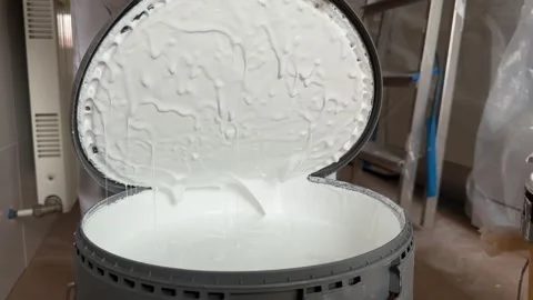 Painter opening a large bucket of white paint for home renovation Stock Footage 341363381