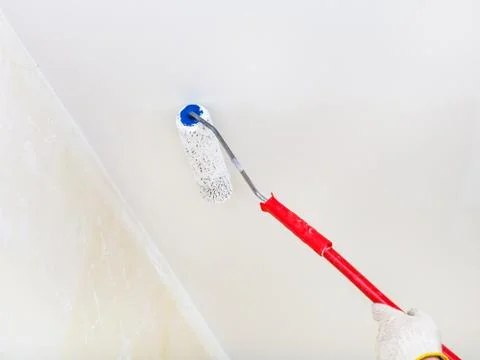 Painter paints the ceiling with white paint Stock Photos