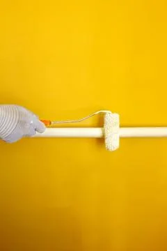 A painter paints a pipe white with a roller, a gloved hand paints a pipe white Stock Photos