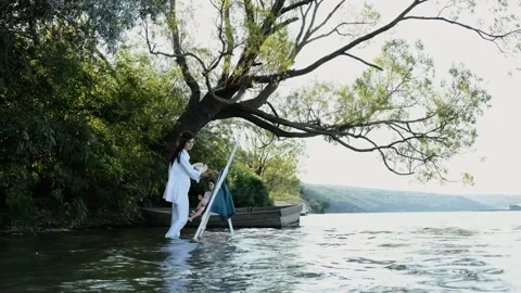 Painter paints on the textile a real view, a girl that is sitting in a boat. Stock Footage 138869910