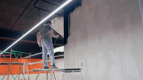 Painter paints the wall with black paint Stock Footage 145973636