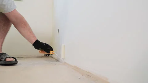 The painter paints the walls white with a roller. Repairs in the room and Stock Footage 243266986