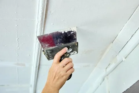 Painter putty ceiling defects using spatula for painting. Stock Photos