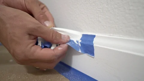 Painter removing masking blue tape from moulding. Stock Footage 129141828