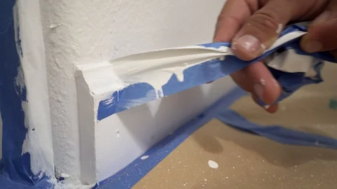 Painter removing masking blue tape from moulding. Stock Footage 129141915