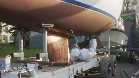 A painter repaints and protects the hull of his boat, in Switzerland Stock Footage 229697259