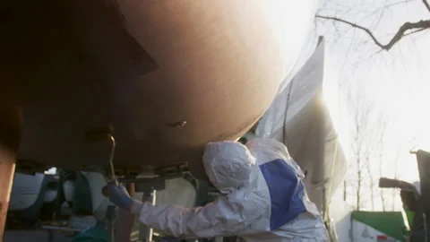 A painter repaints and protects the hull of his boat, in Switzerland Stock Footage 229704101