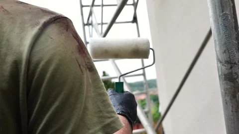 Painter with a roller in his hands on the background of scaffolding Stock Footage 320633026