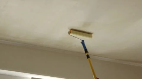 Painter rolling liquid primer coat over apartment ceiling surface Stock Footage 340403980