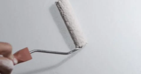 Painter rolls white paint across smooth interior wall with paint roller. St.. Stock Footage 348442478