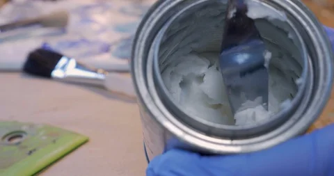 Painter scraping out cold wax or a paste media from a small can Video stock 120638697