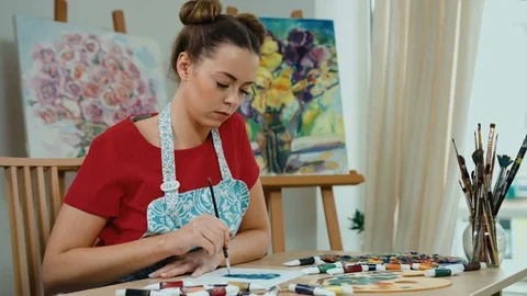 Painter sitting at table and drawing on a piece of paper in art studio Stock Footage 74202792