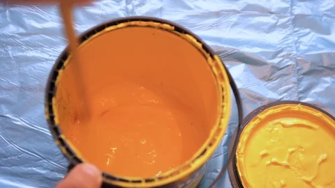 Painter stirring yellow wall paint in a can with a stick. Stock Footage 120009892
