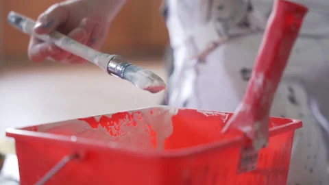 A painter takes white paint in a red seal in slowmotion Video stock 149127393