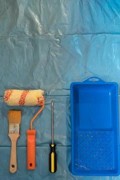 Painter tools on a foil - brush, roll, screwdriver, plastic tray. Stock Photos