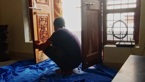 Painter using brush for Applying Varnish to wooden door in residential home at Stock Footage 334216288