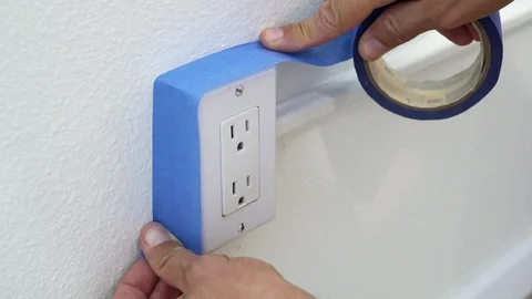 Painter Using Masking Blue Tape to Secure Electric Outlet.  Stock Footage 129137730