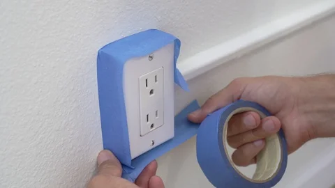 Painter Using Masking Blue Tape to Secure Electric Outlet.  Stock Footage 129137752