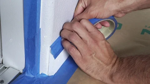 Painter Using Masking Blue Tape to Secure Baseboard, Moulding. Renovation. Stock Footage 129138757