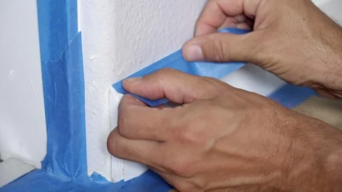 Painter Using Masking Blue Tape to Secure Baseboard, Moulding. Renovation. Stock Footage 129138851