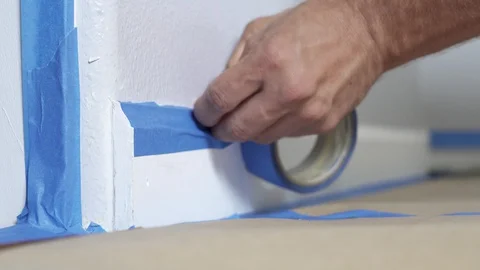 Painter Using Masking Blue Tape to Secure Baseboard, Moulding. Renovation. Stock Footage 129138971
