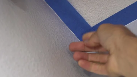 Painter Using Masking Blue Tape to Secure Ceiling. Preparation For Room to Paint Stock Footage 129139118