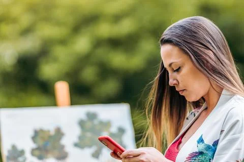 Painter using a mobile in a park Stock Photos