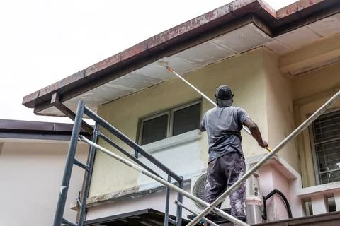 Painter worker adding undercoat foundation paint onto ceiling with roller at Stock Photos
