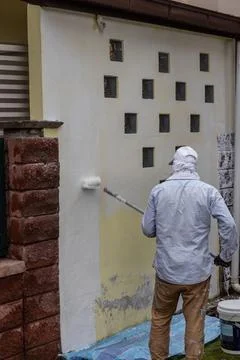 Painter worker adding undercoat foundation paint onto wall with roller at r.. Stock Photos