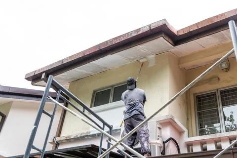 Painter worker adding undercoat foundation paint onto ceiling with roller a.. Stock Photos