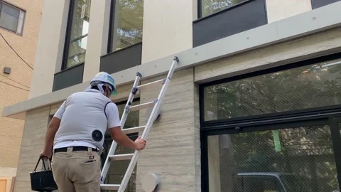 Painter worker on ladder with special cooling fan jacket to beat the heat. Stock Footage 137576706