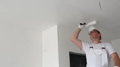 Painter worker with roller painting ceiling surface into white Stock Footage 131397225