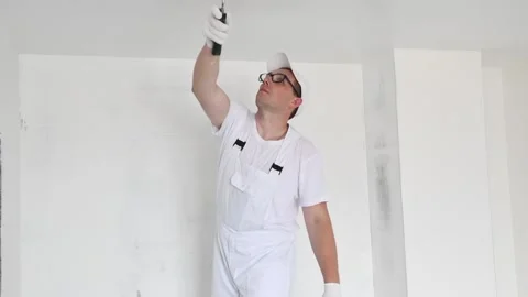 Painter worker with roller painting ceiling surface into white Video stock 131397239