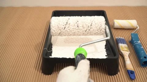 Painter worker wets paint roller and prepares for painting Stock Footage 125713860