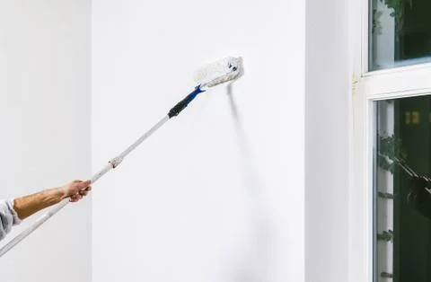 Painter working with paint roller and brushes to paint the room Stock Photos