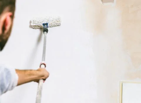 Painter working with paint roller and brushes to paint the room Stock Photos