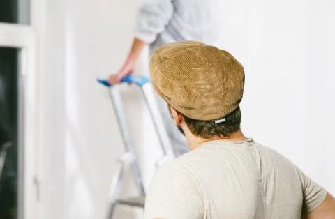Painter working with paint roller and brushes to paint the room Stock Photos