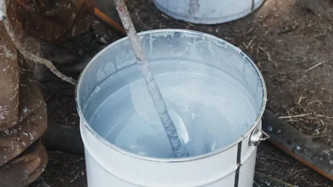 A painter working stirs silver paint in a bucket using a special electric tool Stock Footage 286340653