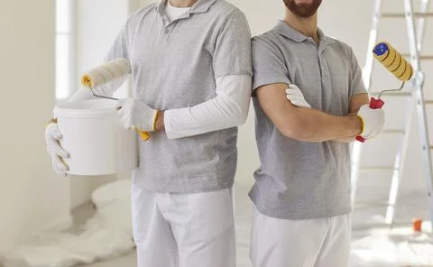 Painters team holding paint rollers, construction workers, professional service Stock Photos