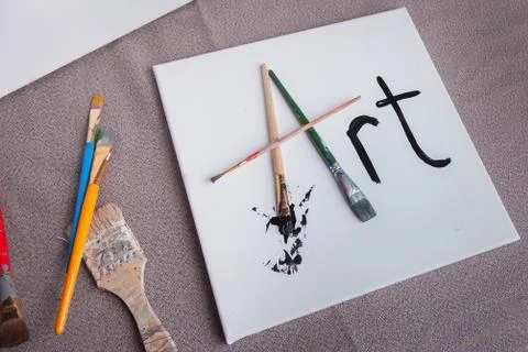 Painters work station paint brushes and white canvas Stock Photos