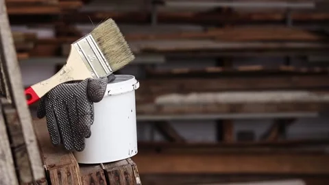 Painter's workplace with a bucket of paint, brush and work gloves Stock Footage 346385090