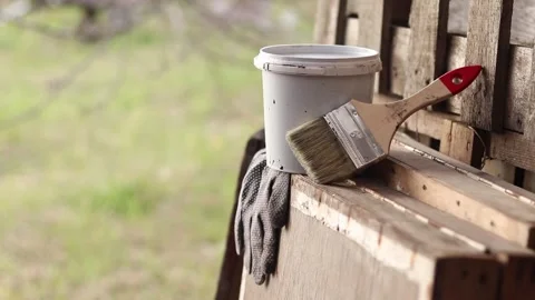 Painter's workplace with a bucket of paint, brush and work gloves on wood Stock Footage 346385104