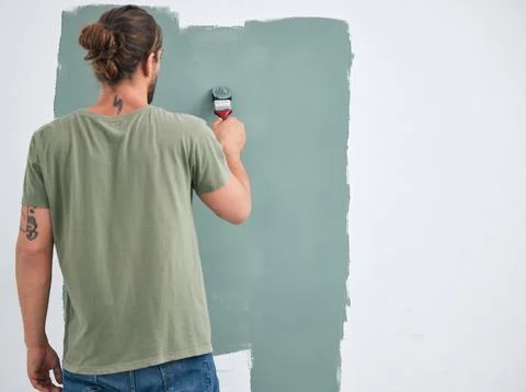 Painting, brush and renovation with a man doing interior DIY in a room for Stock Photos