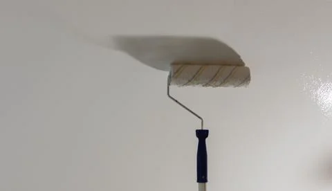 Painting the ceiling with a paint roller reflection of light Foto stock