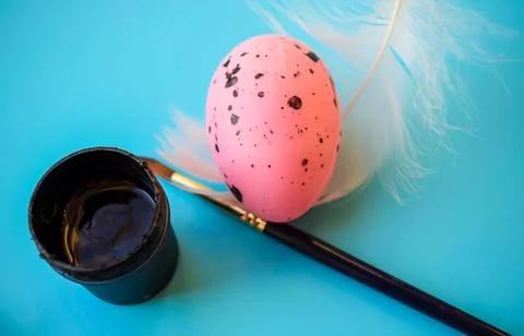 Painting Easter Egg with Brush and Paint Jars on Blue Background Stock Photos