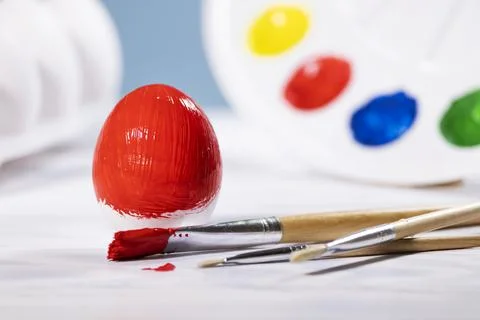 Painting Easter eggs, Preparation for spring holiday, Red egg with palette of Stock Photos