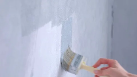 Painting white wall in gray using paintbrush, hand closeup, side view. Stock Footage 123412369